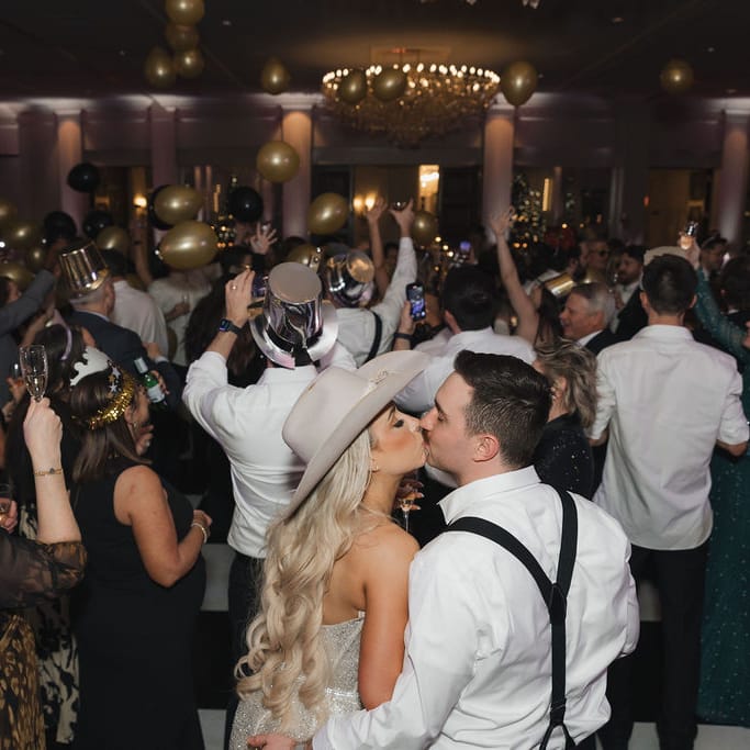 Bride and groom kiss on crowded dance floor during New Year's balloon drop at The Pfister