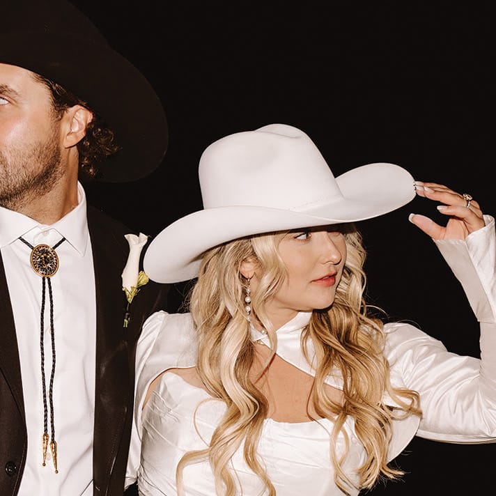 Morgan and Justin pose in their western hats at their wedding reception