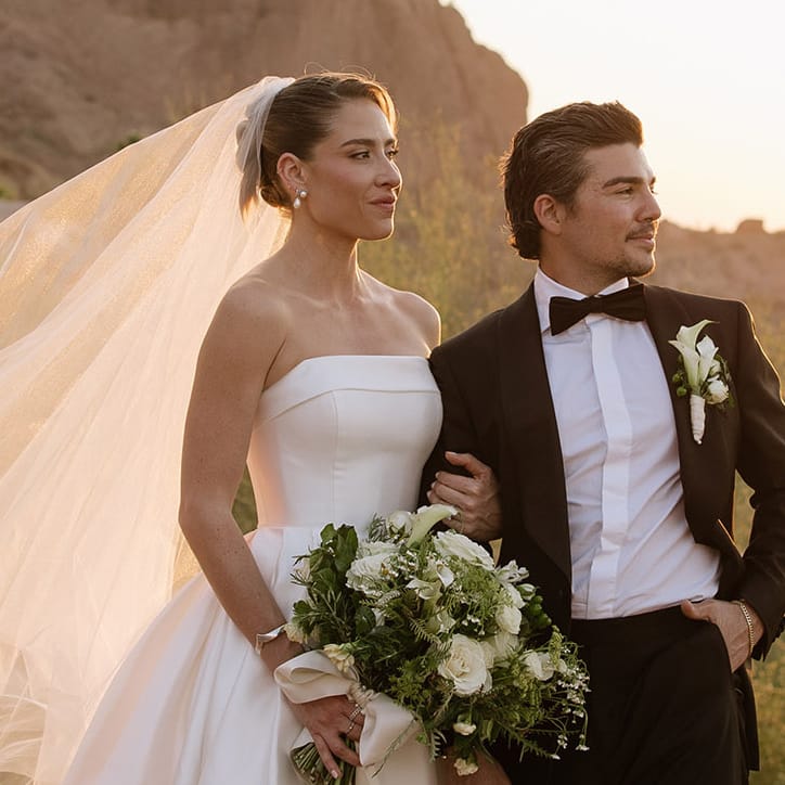 Bride and groom pose on the rocks of Camelback Mountain with the golden hour casting a glow behind them