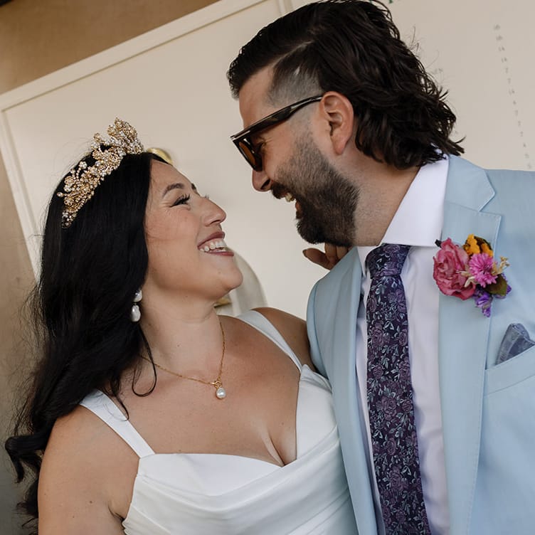 Danielle and Brandon pose in front of their custom signage at their wedding