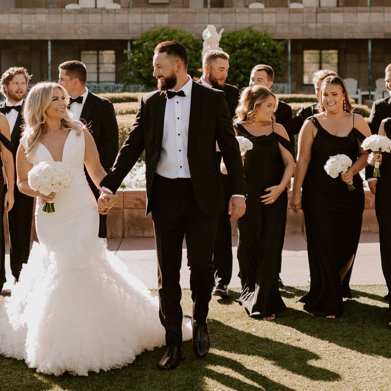 Bride and groom smile with their wedding party dressed in black