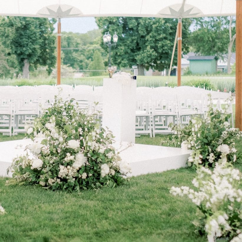 Lush tented ceremony featuring white florals at Happy Hollow Club