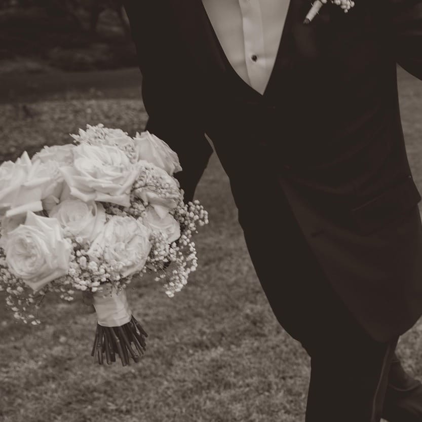 Bride and groom holding hands and walking in black and white at Villa Loriana