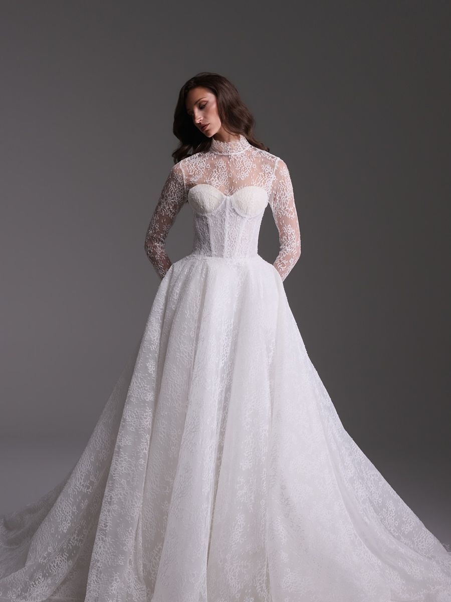 Guillermo Pharis Amanda wedding dress from the Fall 2027 Everlasting collection, featuring a sheer high-neck lace overlay, long sleeves, corset bodice and full ballgown skirt.