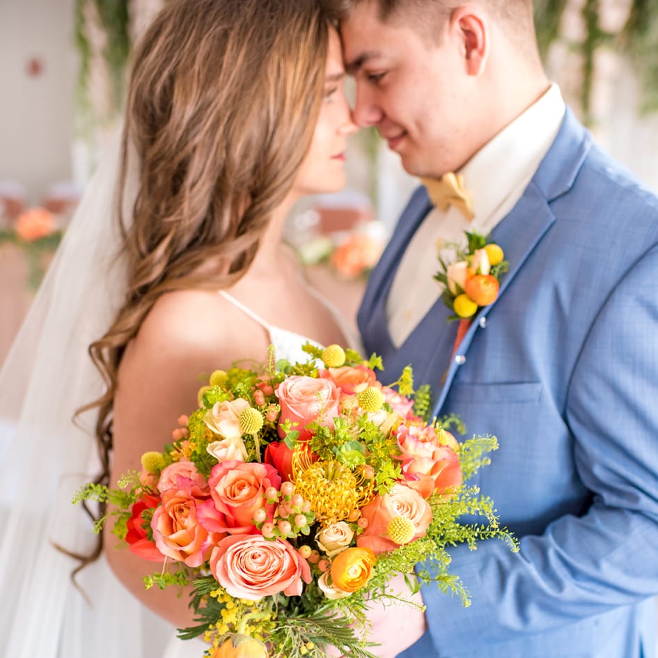 Couple shares a moment while holding a bright pink, orange and yellow bouquet at Par 4 Golf and Resort